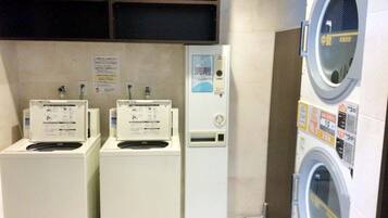 A laundry facility with three washing machines and a dryer, each with control panels and instructions.