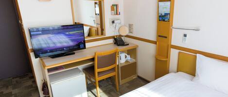 Una habitación de hotel con cama, escritorio con computadora, silla, refrigerador pequeño, reloj y espejo.
