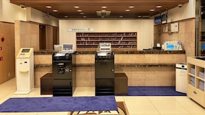 A reception area with a 'FRONT' sign, a counter with a computer, a self-service kiosk, and a small seating area.