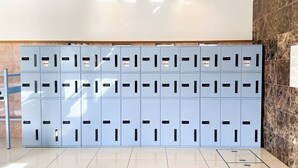 A row of light blue lockers with black handles and labels, arranged against a wall with a marble pattern.