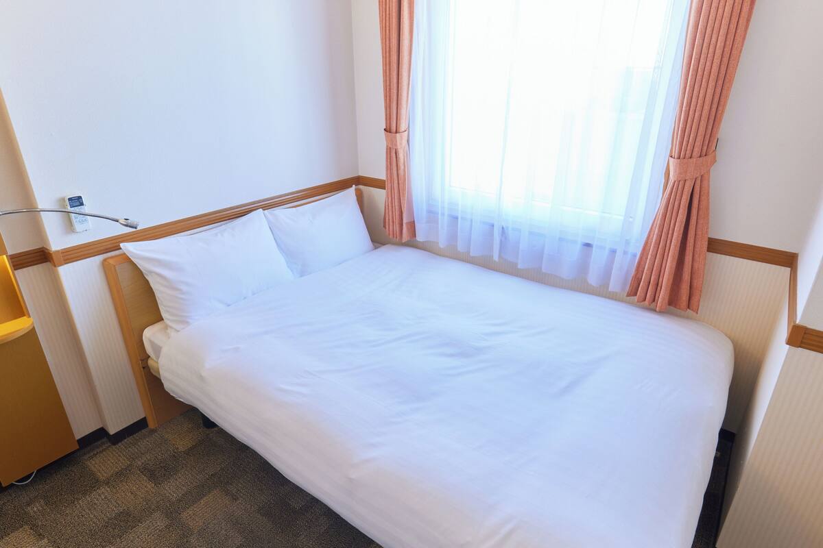 Ein ordentlich bezogenes Bett mit weißen Leinentüchern in einem Hotelzimmer.