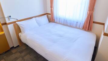 A neatly made bed with white linens in a hotel room.