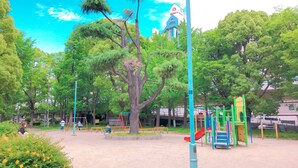 A playground with various play structures, surrounded by trees and a building with a tower in the background. - Toyoko Inn Osaka Hankyu Juso Station Nishi (Osaka)
