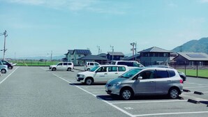 A parking lot with several cars, including a white van and a silver hatchback.