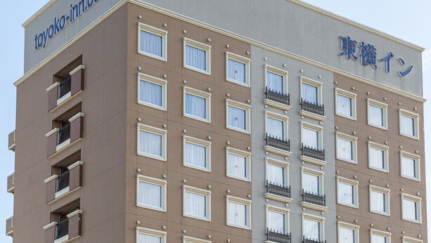 A multi-story hotel with a beige and gray facade, featuring a series of windows and balconies.