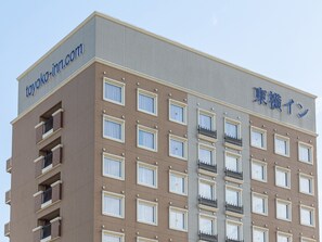 Een meerlaags hotel met een gevel in beige en grijstinten, voorzien van ramen en balkons.