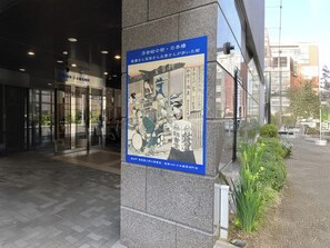 A building entrance with a large poster, glass doors, and a paved walkway. - Toyoko Inn Nihombashi Bakurocho (Tokyo)
