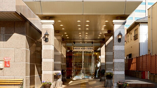 A hotel entrance with a covered walkway, stone pillars, and potted plants. - Toyoko Inn Yokohama Shinkoyasu Ekimae (Yokohama)