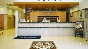 A hotel reception area with a marble counter, a clock, and a sign that reads "FRONT".