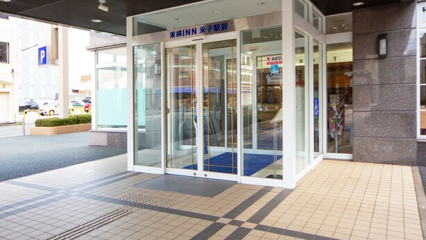 A modern building entrance with glass doors, a blue carpet, and a sign indicating an emergency room. - Toyoko Inn Yonago Ekimae (Yonago)