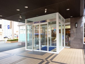 A modern building entrance with glass doors, a blue carpet, and a sign indicating an emergency room.