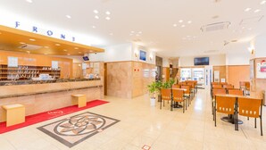 A hotel reception area with a reception desk, seating area, vending machines, and a large screen. - Toyoko Inn Yonago Ekimae (Yonago)