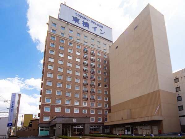 A multi-story hotel with a prominent sign for 'toyoko inn' and a large billboard above.