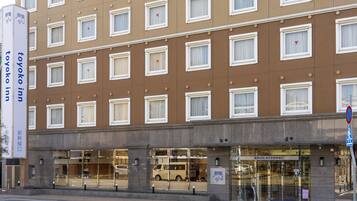 Un hotel de varios pisos con fachada marrón, múltiples ventanas y escaparate con puertas de cristal.