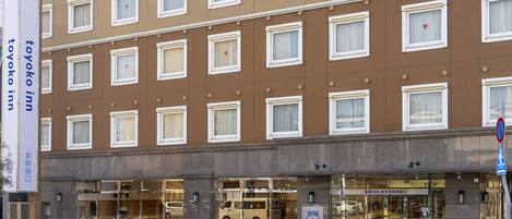 A multi-story hotel with a brown facade, multiple windows, and a storefront with glass doors.