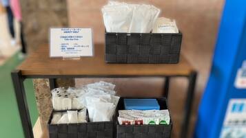 A hotel room with a wooden table displaying toiletries and a sign with Japanese text.
