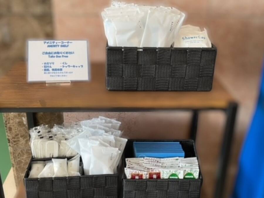 A hotel room with a wooden table displaying toiletries and a sign with Japanese text.