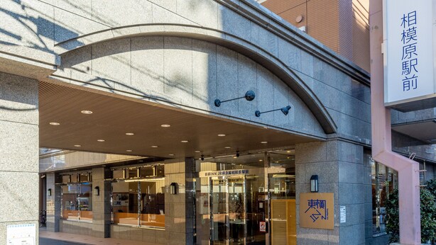 Une entrée moderne avec un passage couvert, des portes en verre et une enseigne indiquant qu’il s’agit d’un hôtel.