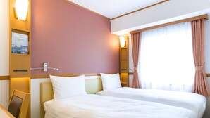 Une chambre d’hôtel avec deux lits, un bureau et une fenêtre avec des rideaux.