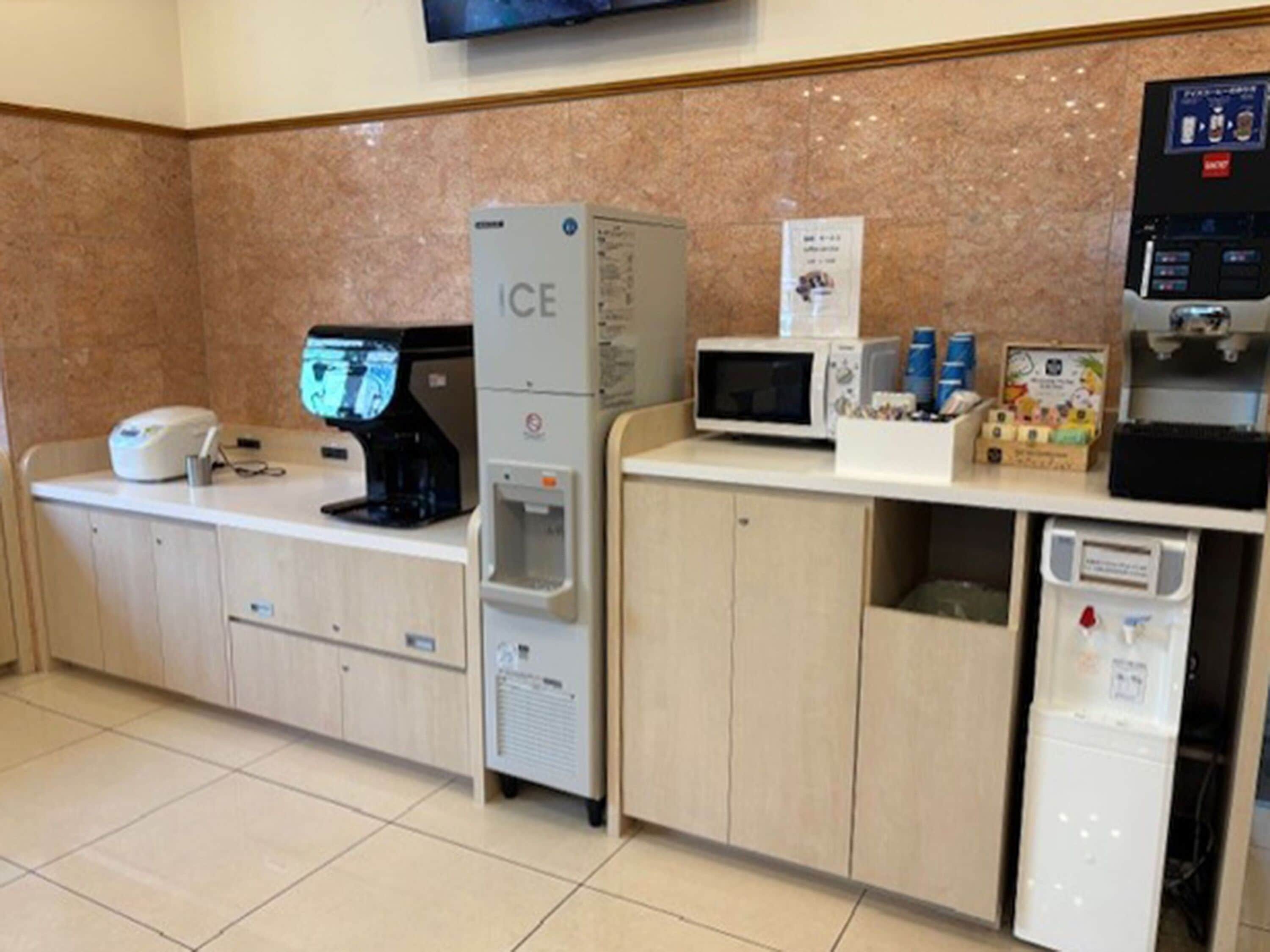 Un espace d’accueil d’hôtel équipé d’une machine à café, d’un distributeur de glaçons, d’un four à micro-ondes et d’un point de service pour se préparer des boissons.