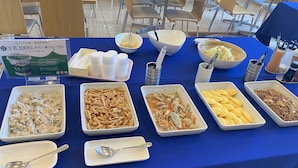 Une table de buffet proposant divers plats, notamment des pâtes, des nouilles et des frites.