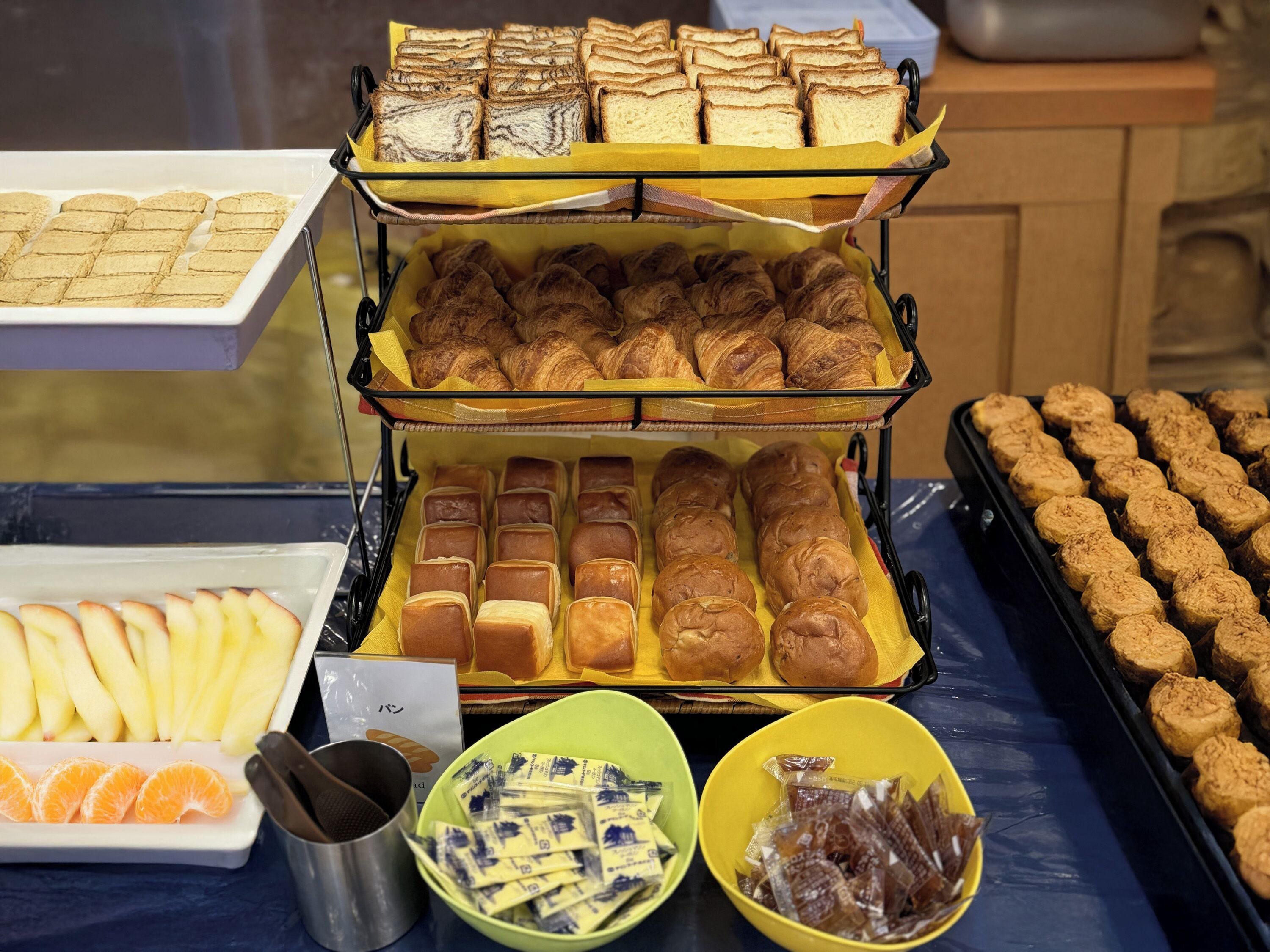 Un buffet proposant une variété de produits de boulangerie, notamment du pain, des viennoiseries et des petits pains.