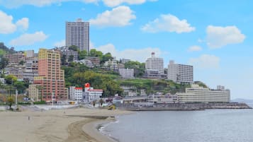 A coastal cityscape with a beach, high-rise buildings, and a rocky shoreline.