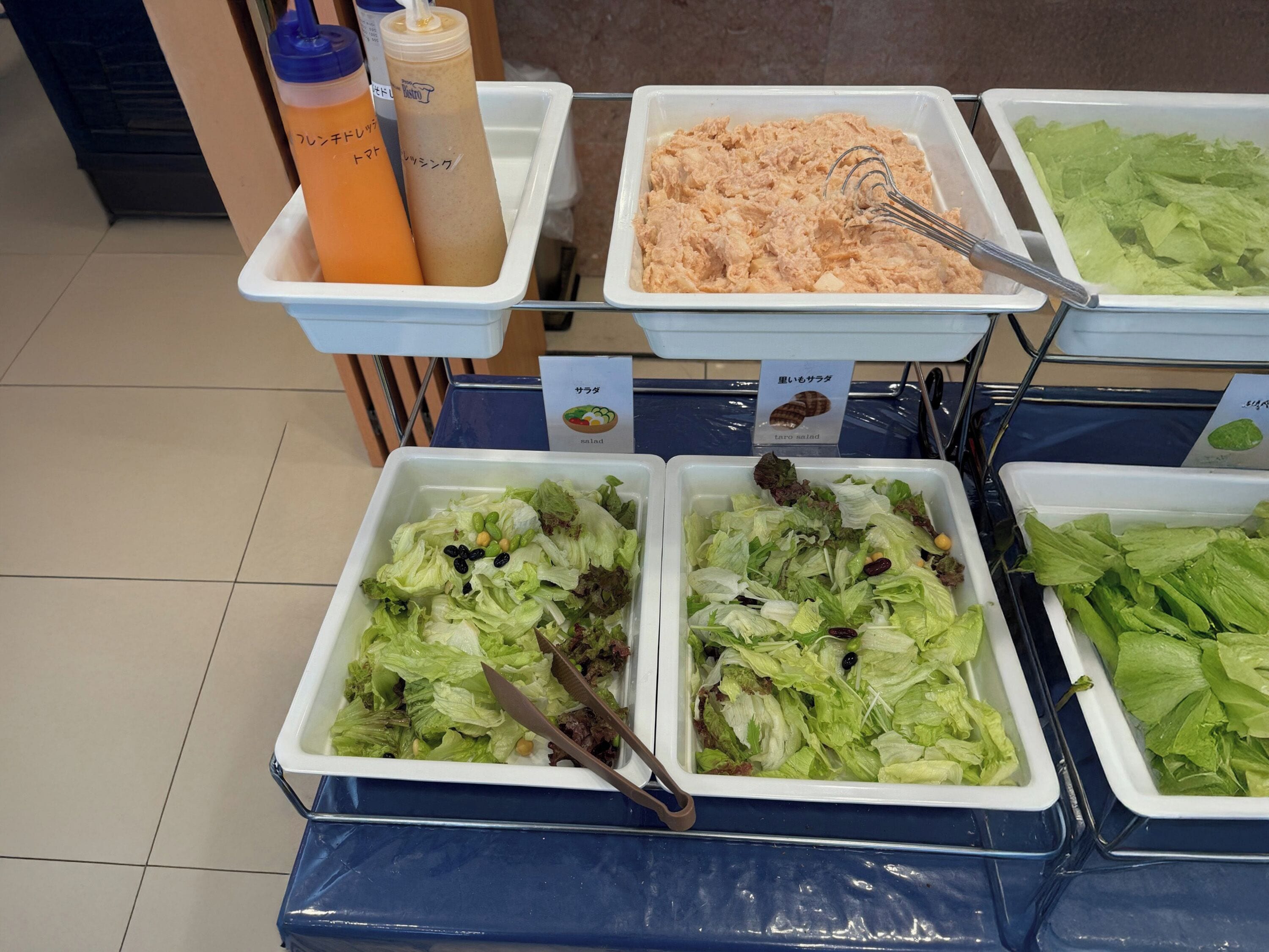 A buffet with various food options including salads, a tuna salad, and beverages.