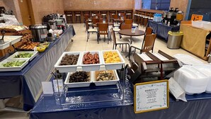 Ein Buffet mit verschiedenen Speisen und einem Schild, das die Frühstückszeiten angibt.