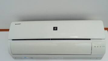 Un equipo de aire acondicionado Sharp blanco montado en una pared.