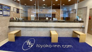 Un comptoir d’accueil avec un tapis bleu et une enseigne indiquant « TOYOKO-INN.COM ».