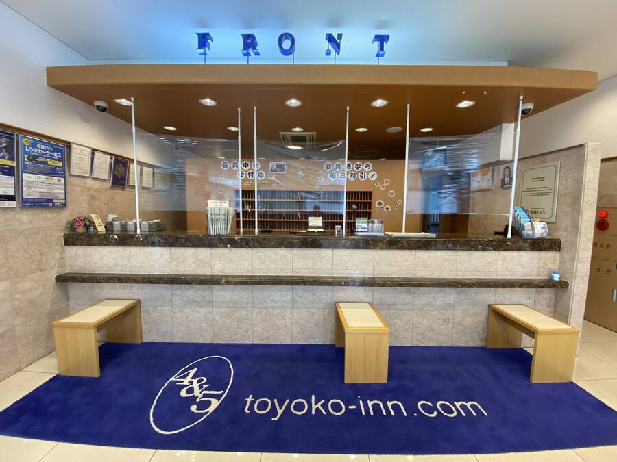 Una recepción con alfombra azul y un letrero que dice TOYOKO-INN.COM.