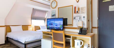 Habitación de hotel con cama, escritorio, silla y una pequeña kitchenette.