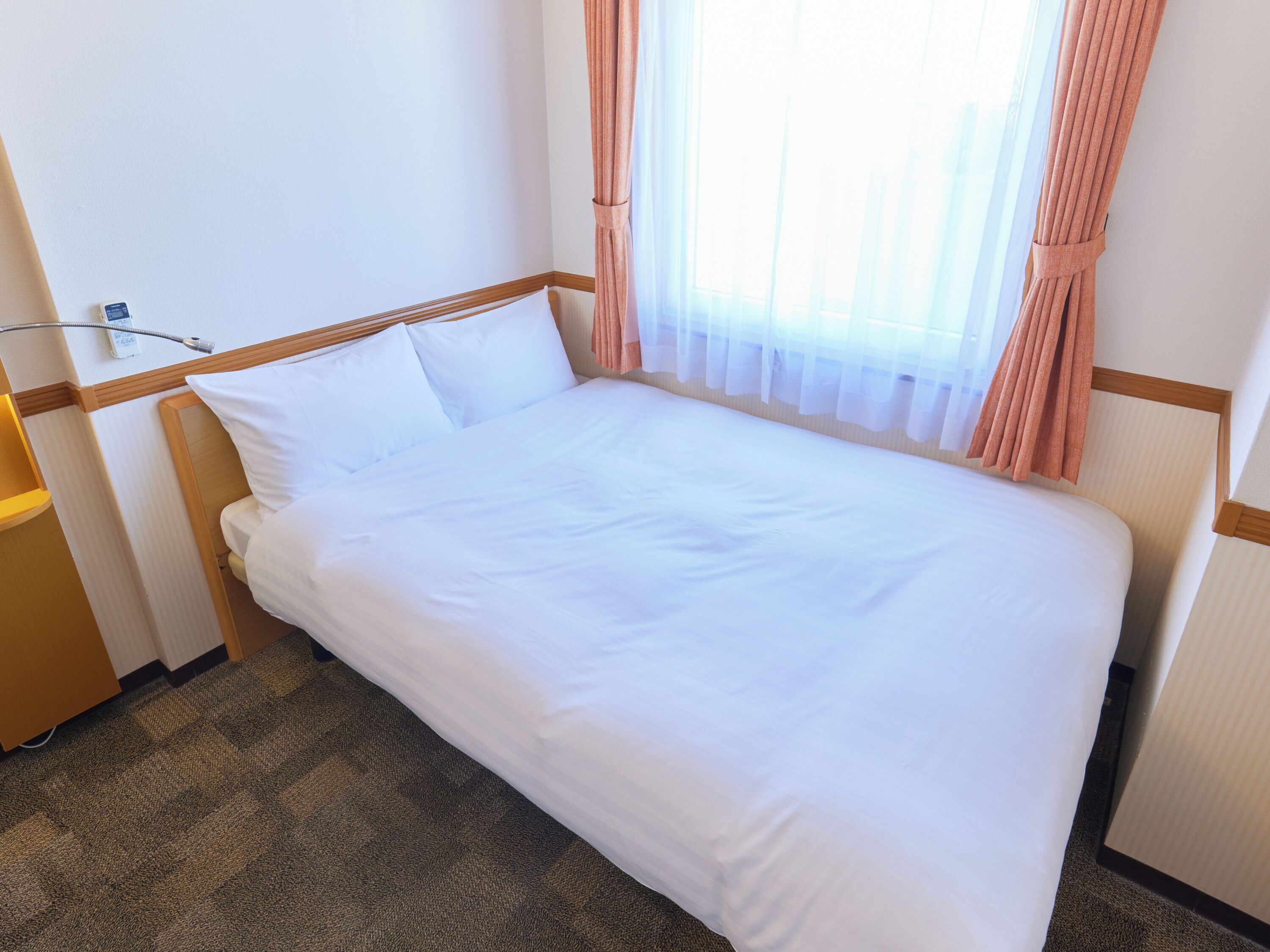 A neatly made bed with white linens in a hotel room.