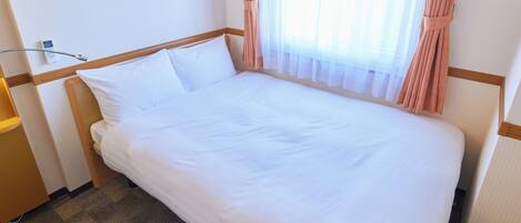 A neatly made bed with white linens in a hotel room.