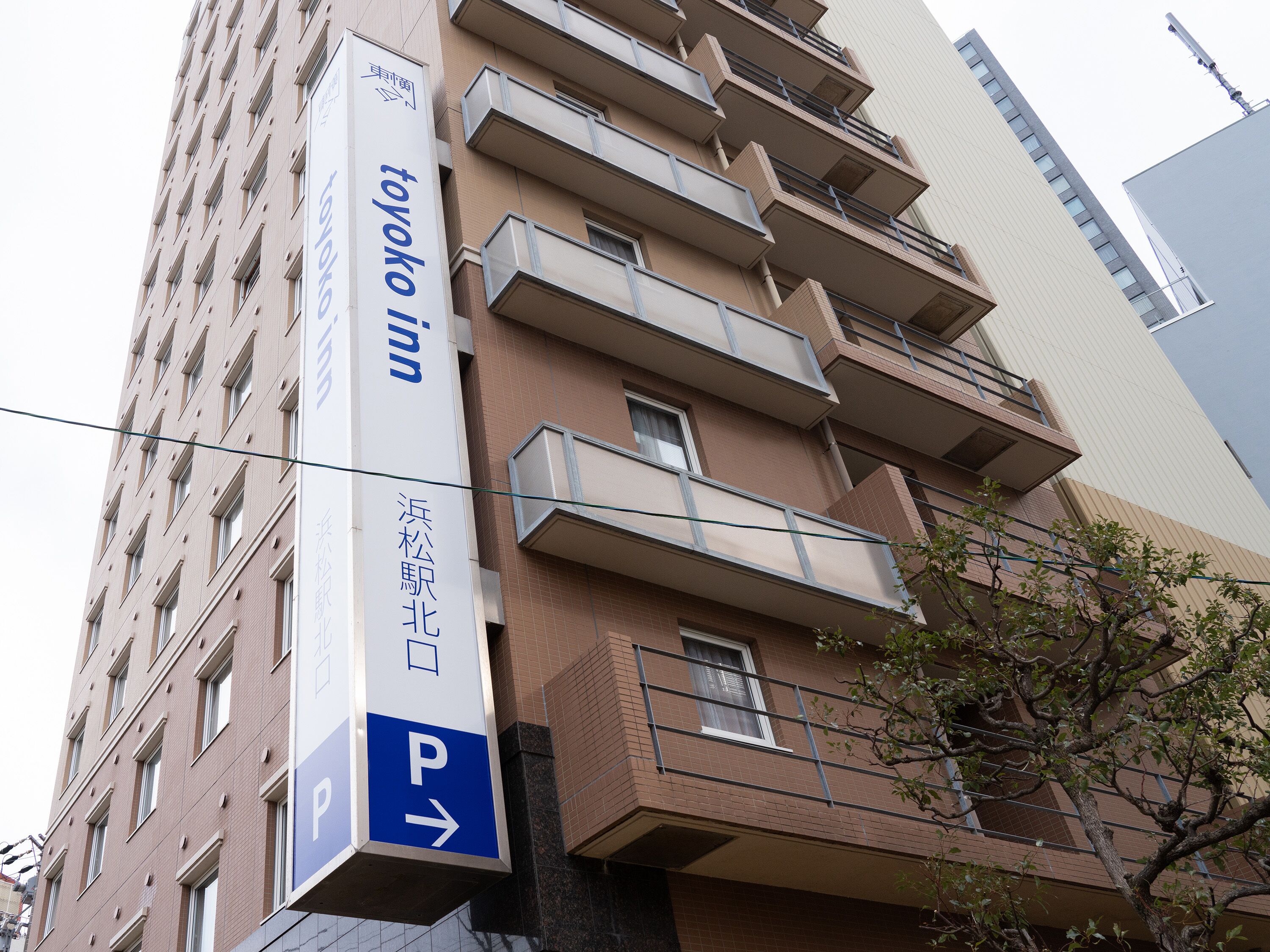 Un grand immeuble avec une enseigne indiquant « Toyoko Inn » et un panneau indiquant la direction du parking.