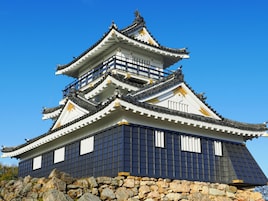 Un castillo japonés tradicional con varios niveles y base de piedra.