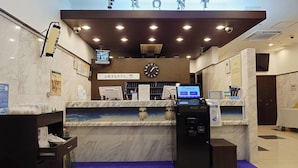 A hotel reception area with a marble counter, a clock, and a digital display. - Toyoko Inn Tokyo Nihombashi Mitsukoshi Mae A4 (Tokyo)
