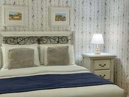 Un letto rifatto con una coperta blu, un poggiatesta bianco e due quadri incorniciati sopra.