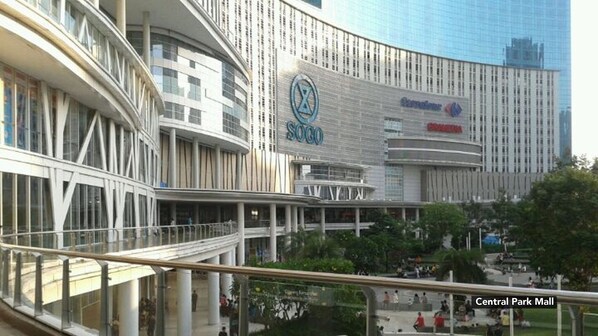 A modern shopping mall with a prominent Sogo store and a central park area visible in the background.