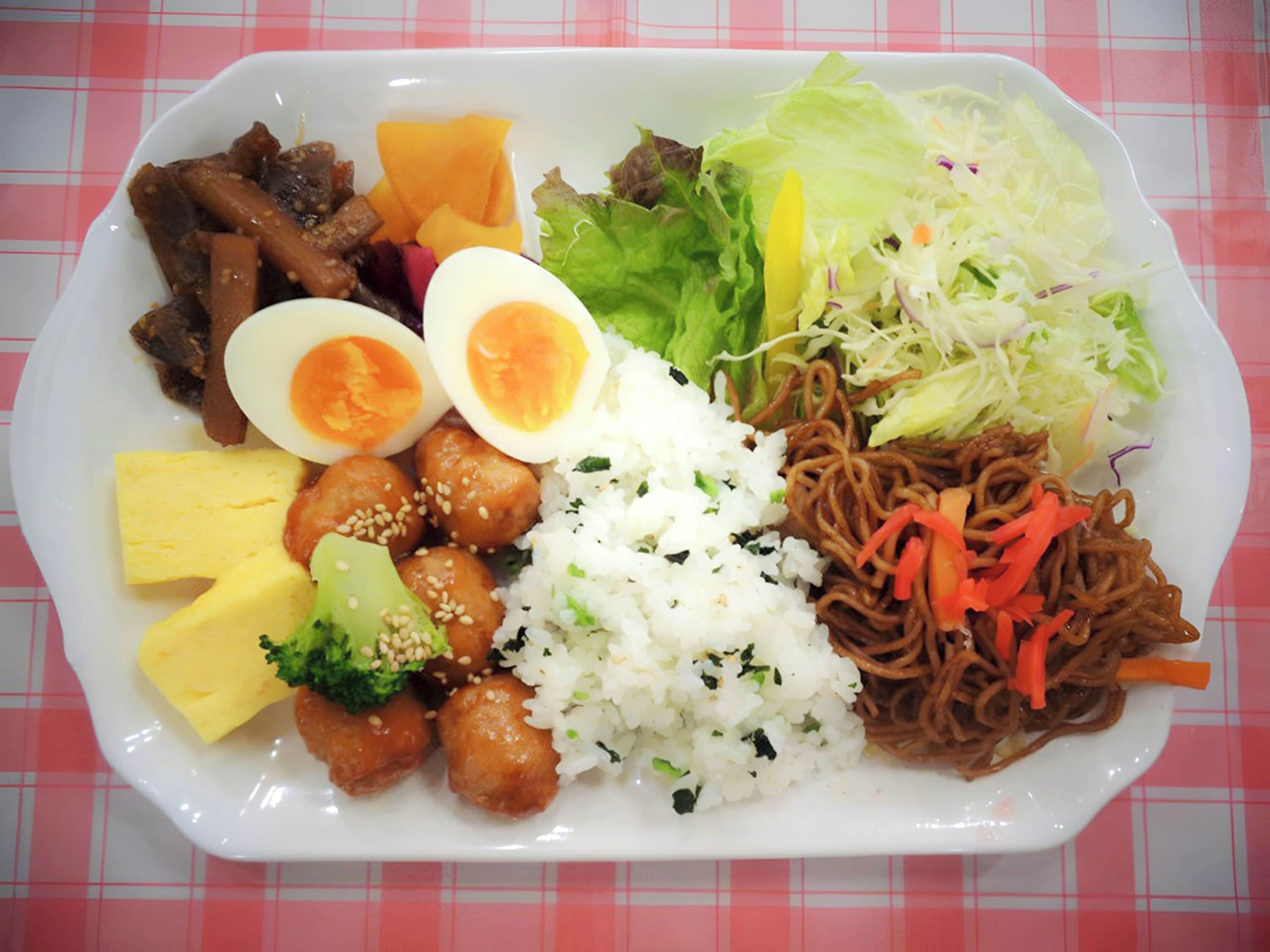 A plate of food with various items including rice, noodles, vegetables, and meat.