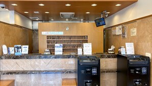 A reception area with a marble counter, a wooden reception desk, and a wall-mounted television. - Toyoko Inn Wako-shi Ekimae (Wako)