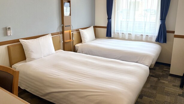A hotel room with two beds, a bedside table, a lamp, a telephone, and a window with curtains. - Toyoko Inn Wako-shi Ekimae (Wako)