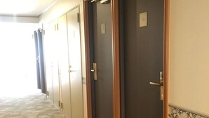 A hallway with a carpeted floor, a wooden door with a lock, and a number sign above it. - Toyoko Inn Wako-shi Ekimae (Wako)