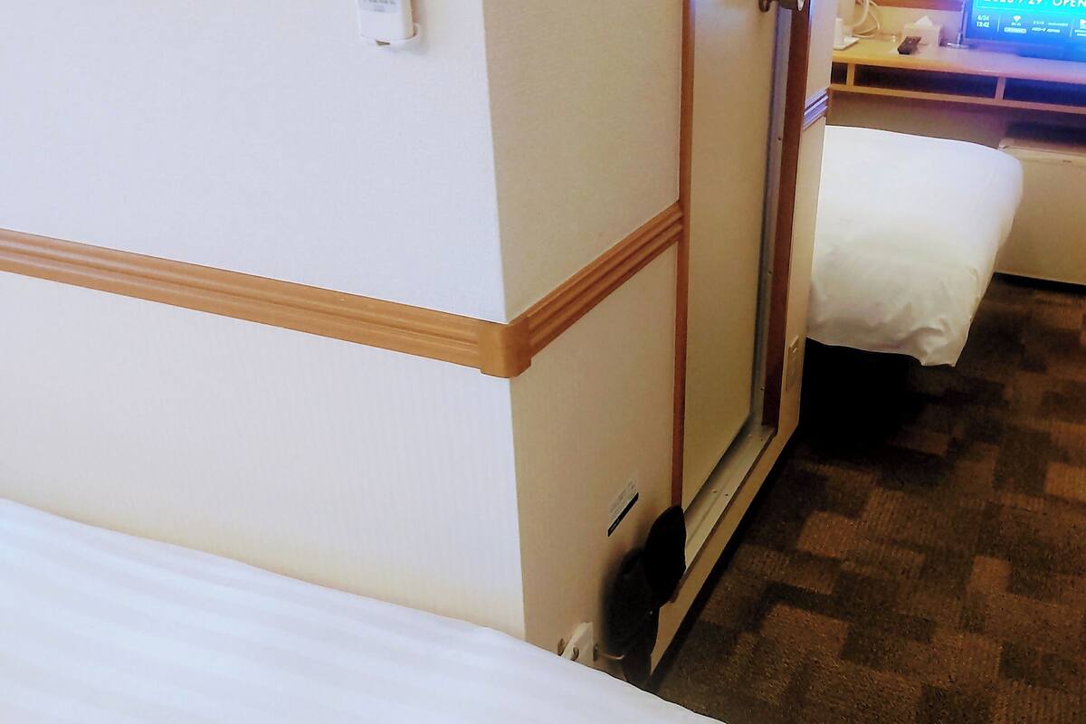 A hotel room with a bed, a desk, and a computer monitor.