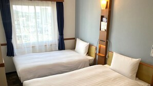 A hotel room with two single beds, a window with sheer curtains, a wall-mounted shelf with reading material, and a bedside table with a lamp. - Toyoko Inn Shin Yamaguchi Station Shinkansen (Yamaguchi)