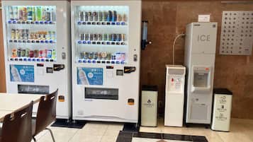A vending machine area with various drink options, a water dispenser, and a trash bin labeled "Cans, Bottle, PETBOTTLE".