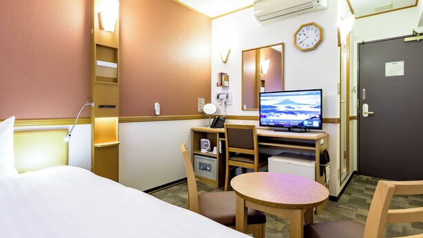 Habitación de hotel con cama, escritorio, silla y televisor que muestra una vista panorámica.