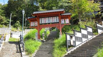 Um tradicional portão torii japonês na base de uma escadaria de pedra que leva a um templo.