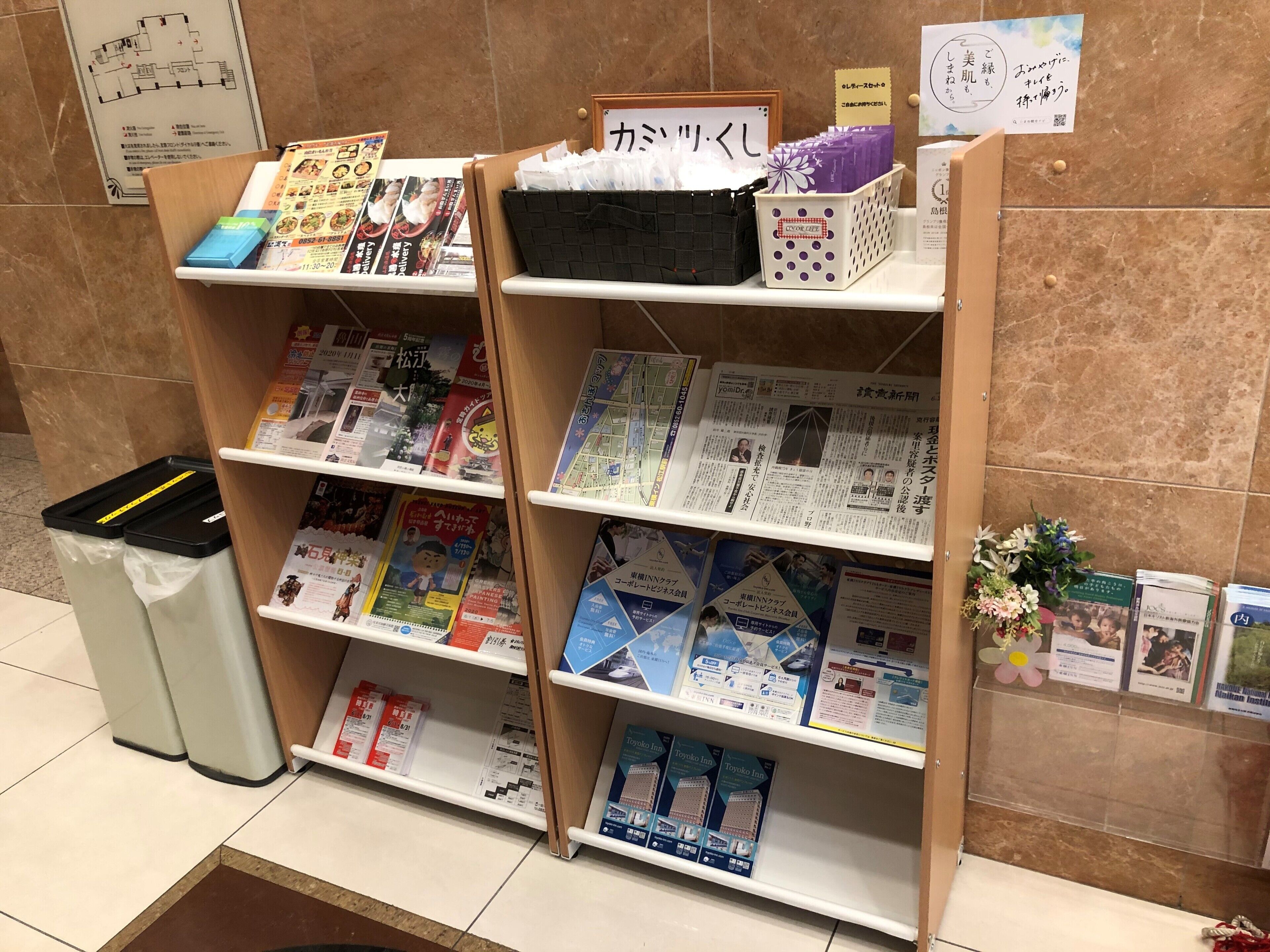 A hotel reception area with a floor plan, magazines, and brochures on shelves.